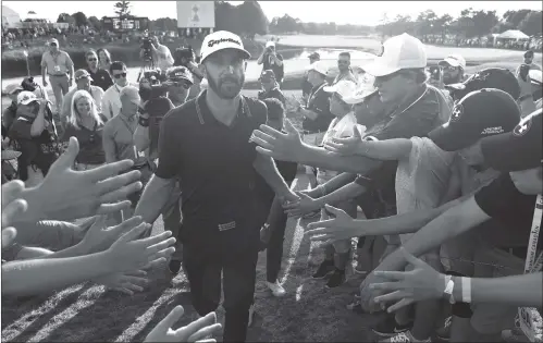  ??  ?? Dustin Johnson celebrates his winning putt on the 18th hole by greeting fans during the final round of the Canadian Open at Glen Abbey Golf Club on Sunday in Oakville, Canada.