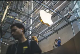  ?? EMMA HOWELLS / THE NEW YORK TIMES ?? A corporate logo hangs above the interior of the Apple store in the SoHo neighborho­od of New York. Company co-founder Steve Jobs said Apple was 90 days from bankruptcy in 1997. Today, Apple is part of a small group of giant companies that dominates the...