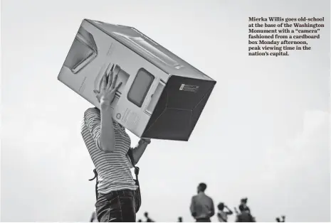  ?? JACK GRUBER, USA TODAY ?? Mierka Willis goes old-school at the base of the Washington Monument with a “camera” fashioned from a cardboard box Monday afternoon, peak viewing time in the nation’s capital.