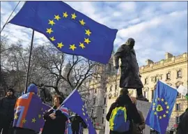  ?? Daniel Leal-Olivas AFP/Getty Images ?? ANTI-BREXIT activists wave EU f lags near a statue of Winston Churchill in London. Brexit is landing “with a rather dull thud,” one political scientist says.