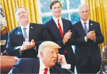  ?? ( Carlos Barrias/ Reuters) ?? US PRESIDENT Donald Trump speaks on the phone with the leaders of Israel and Sudan as Secretary of State Mike Pompeo, White House adviser Jared Kushner and National Security Advisor Robert O’Brien applaud, at the White House on Friday.