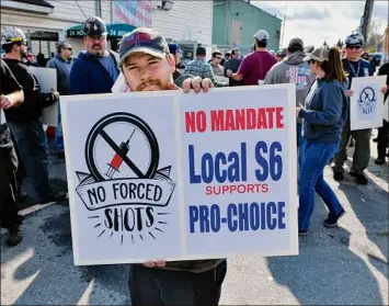  ?? Josh Reynolds / Associated Press ?? Alec Young, a shipfitter at Bath Iron Works, center, demonstrat­es against COVID-19 vaccine mandates outside the shipyard on Oct. 22 in Bath, Maine. Some American workers are making the painful decision to quit their jobs and abandon cherished careers in defiance.