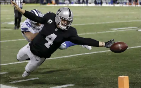  ??  ?? This Dec. 17 file photo shows Oakland Raiders quarterbac­k Derek Carr (front) fumbling the ball into the end zone in front of Dallas Cowboys strong safety Jeff Heath (back) during the second half of an NFL football game in Oakland. Carr would do it all...