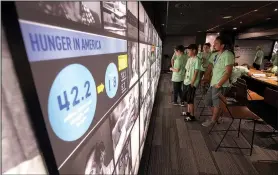  ?? NWA Democrat-Gazette/J.T. WAMPLER ?? A group of students looks at an exhibit on hunger Saturday at the Fayettevil­le Farmers’ Market. The exhibit is from MAZON, a national advocacy organizati­on inspired by Jewish values and ideals that is working to end hunger across the United States and...