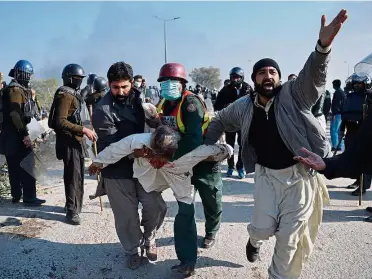  ??  ?? Anger in the streets: An injured protester being carried away from clashes with police in Islamabad. — AFP