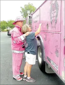  ?? Lynn Atkins/The Weekly Vista ?? John Rhyne, a firefighte­r from Ponca City, Okla., helps Betty Hamilton sign her name on a Pink Heals truck at Highlands Oncology in Rogers.