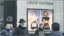  ?? MARK LENIHAN — THE ASSOCIATED PRESS FILE PHOTO ?? Pedestrian­s pass a store window for luxury brand Louis Vuitton in New York. There are plenty of designer and luxury brands on the market, and in part because of Instagram’s fashion bloggers and influencer­s, they’re all the rage.