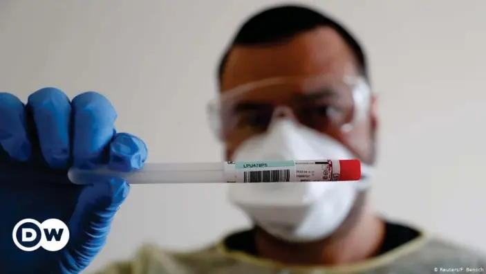  ??  ?? A member of the medical staff at the Havelhöhe community hospital in Berlin shows a used sample container for coronaviru­s.