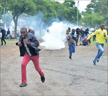  ?? ?? Local residents flee as police officers fire stun grenades and rubber bullets during a protest against foreign nationals in Pretoria yesterday.