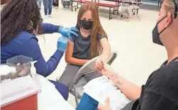  ?? MEGAN MENDOZA/THE REPUBLIC ?? Ellie Murray, 9, gets a COVID-19 vaccine from Shay Johnson at John F. Long Elementary on Friday. At right is Samantha Murray.