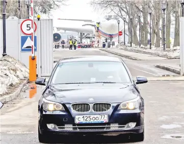  ?? — AFP photo ?? A car drives out of the airport as the Russian Il-96 jet that brought back 46 Russian diplomats and their family members is seen at the parking place of the Russian Ggvernment airport Vnukovo II in Mosow.