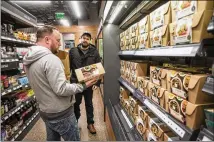  ?? STEPHEN BRASHEAR / GETTY IMAGES ?? Shoppers Peter Ray (left) and Peter Freese examine pre-made meals Monday at the Amazon Go convenienc­e store in Seattle, which is now open to the public.