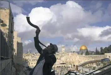  ?? Uriel Sinai/The New York Times ?? A Jewish man blows a shofar with the Dome of the Rock in the distance on Wednesday in Jerusalem. President Donald Trump recognized Jerusalem as the capital of Israel on Wednesday, despite warnings the action could damage prospects for Mideast peace.