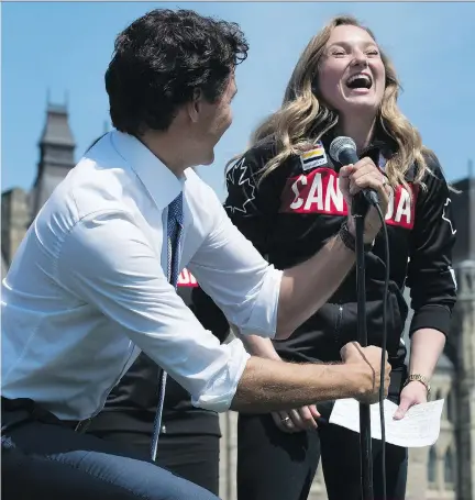  ?? ADRIAN WYLD/THE CANADIAN PRESS ?? Prime Minister Justin Trudeau lowers the microphone for Canadian gold medal winner Rosie MacLennan after announcing she’ll be the flag bearer for the upcoming Rio Games.