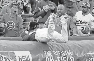  ?? JOSE CARLOS FAJARDO/STAFF ?? A foul ball lies on Ryon Healy’s back after the A’s third baseman failed to make a catch on the field tarp in the second inning.