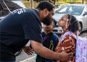  ?? Lucy Schaly/Post-Gazette ?? Christophe­r Gary gives his kids Chance, 6, center, and Marley, 8, a quick kiss before they go to school at Pittsburgh Morrow PreK-8 in Brighton Heights on Thursday.