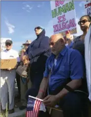  ?? RUSSELL CONTRERAS — THE ASSOCIATED PRESS FILE ?? In this file photo, Kadhim Al-bumohammed, kneeling right, a 64-year-old Iraqi refugee in the U.S., listens to speakers at an Albuquerqu­e rally in his honor. As cities and towns host July 4th parades and fireworks shows, some minority residents are...