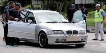  ??  ?? Police officers checking the car used by the three gang members who were killed in a shootout with Johor police.