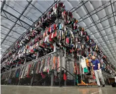  ?? Matt York/Associated Press file photo ?? ■ Thousands of garments are stored on a three-tiered conveyor system March 12 at the ThredUp sorting facility in Phoenix.