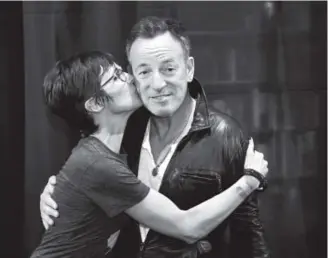  ?? Photos by Andy Cross, The Denver Post ?? Cathy Esposito plants a kiss on Bruce Springstee­n’s cheek at the Tattered Cover Book Store on East Colfax Avenue in Denver on Wednesday.