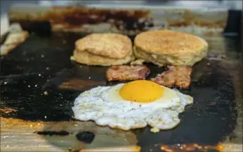  ??  ?? Egg, bacon and biscuits cook on the stainless-steel grill of Soul Biscuit.