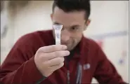  ?? COURTESY OF PENN STATE HEALTH ?? Ty Achtermann, a third-year medical student at Penn State College of Medicine in Hershey, examines his saliva sample during COVID-19 testing for students returning after the holiday break in early December.