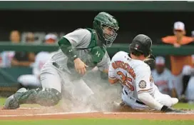  ?? GAIL BURTON/AP ?? Orioles designated hitter Adley Rutschman is tagged out by Athletics catcher Shea Langeliers in the first inning Sunday in Baltimore.