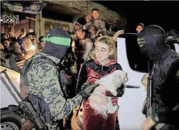  ?? /Reuters ?? Moral support: Mia Leimberg holds her dog, Bella, while she and others are handed over by Hamas militants to members of the Internatio­nal Committee of the Red Cross.