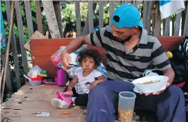  ?? MAURO PIMENTEL / AFP / GETTY IMAGES ?? A Venezuelan man and his daughter eat a meal on the side of a road in Boa Vista, Roraima state, Brazil. Nearly 25,000 Venezuelan­s are living in the city of 300,000.
