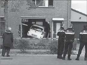  ??  ?? Politie agenten staan op de plek waar de auto een woning binnen reed in Helmond. (Foto: AD.NL)