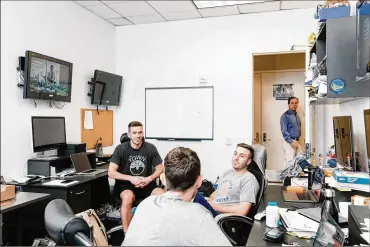  ?? THE NEW YORK TIMES PHOTOS BY JASON HENRY / ?? From left, the video room crew, James Laughlin, Nick Kerr and Jacob Rubin, as the Golden State Warriors’ owner Joe Lacob walks by, at the team’s practice facility in Oakland on May 27. “These guys know more than anyone else,” said the assistant coach Bruce Fraser. “And I’m not saying basketball-wise — they’re learning — but they know more about everything to do with our team, because everyone comes in here. It’s almost like a barbershop.”