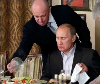  ?? AP PHOTO ?? In this Friday, Nov. 11, 2011, file photo, Yevgeny Prigozhin (left) serves food to Russian Prime Minister Vladimir Putin during dinner at Prigozhin’s restaurant outside Moscow, Russia.