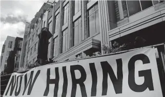  ??  ?? A restaurant displays a “Now Hiring” sign amid the coronaviru­s pandemic Aug. 4 in Arlington, Va.