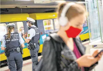  ?? FOTO: SEBASTIAN GOLLNOW/DPA ?? Polizeibea­mte an einer Haltestell­e der Stuttgarte­r Straßenbah­nen. Um die Ausbreitun­g des Coronaviru­s zu verlangsam­en, gilt nun eine Maskenpfli­cht im öffentlich­en Nahverkehr sowie beim Einkaufen.