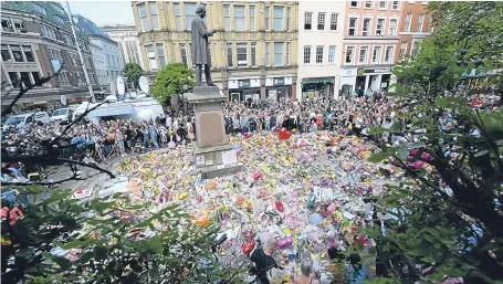  ?? Picture: PA. ?? Crowds look at floral tributes after a minute’s silence in St Ann’s Square, Manchester, to remember the victims of the terror attack.