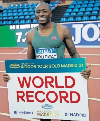  ??  ?? Grant Holloway posa con el cartel que acredita su récord del mundo.