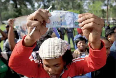  ?? Bloomberg News/DEAN HUTTON ?? A well-wisher holds up a 100 rand bill bearing the image of Nelson Mandela on Wednesday after the former South African president’s body passed by in a procession to the Union Buildings in Pretoria where it is to lie in state.