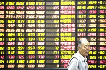  ??  ?? An investor walks past an electronic stock board at a securities brokerage in Shanghai on Oct. 13, 2017. — WP-Bloomberg photo