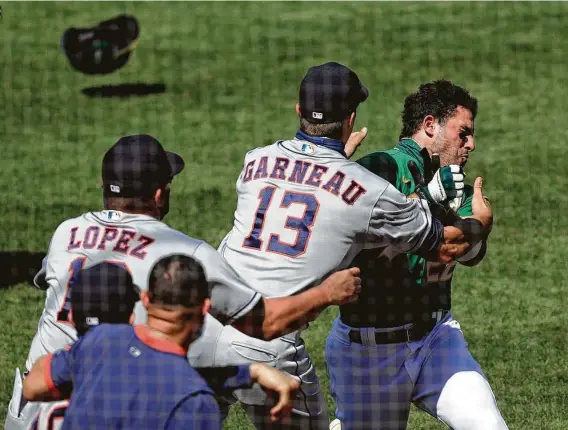  ?? Carlos Avila Gonzalez / San Francisco Chronicle ?? Astros catcher Dustin Garneau helped subdue the A’s Ramon Laureano, who charged the Houston dugout after getting hit by a pitch for the second time Sunday.
