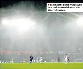  ??  ?? > Last night’s game was played in atrocious conditions at the Liberty Stadium