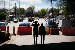  ?? Associated Press ?? n Pedestrian­s walk down a closed portion of Piedmont Avenue on Friday in Atlanta, Ga., near an overpass that collapsed from a large fire on Interstate 85. Atlanta’s dreadful rushhour traffic got even worse Friday, the morning after a raging fire...