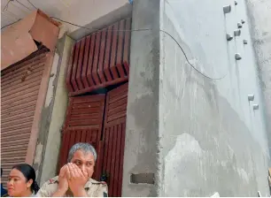  ?? PTI ?? Policemen stand near the wall where 11 pipes seen protruding out of the house, where 11 members of the same family allegedly committed suicide, at Burari, in New Delhi. According to neighbours, the pipes were installed three to four months ago. —