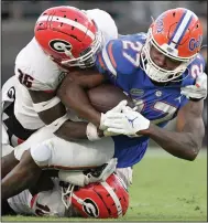  ?? (AP/Phelan M. Ebenhack) ?? Georgia defensive backs Latavious Brini (top) and Lewis Cine tackle Florida running back Dameon Pierce (27) during the second half of the top-ranked Bulldogs’ 34-7 victory over the Gators on Saturday in Jacksonvil­le, Fla.