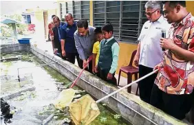  ??  ?? Sharul Azlan (right) together with school staff and students fishing out the crabfish from the pond. Bernama
—