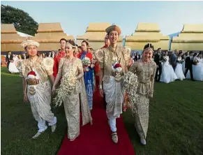  ??  ?? Here come the brides: Couples wearing traditiona­l Sri Lankan wedding attire walking together at the ceremony.