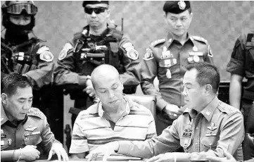  ??  ?? Poompanmou­ng (right) sits next to Sotangkul centre) during his arrest at the police headquarte­rs in Bangkok. — AFP photo