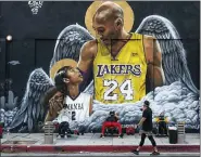  ?? DAMIAN DOVARGANES — THE ASSOCIATED PRESS ?? People lift weights on a sidewalk outside the Hardcore Fitness gym, due to COVID-19restrict­ions, under a mural honoring NBA star Kobe Bryant and his daughter Gigi near Staples Center in downtown Los Angeles, Monday, Jan. 25, 2021.