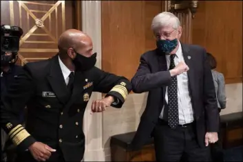  ?? Michael Reynolds The Associated Press ?? Surgeon General Jerome Adams and Dr. Francis Collins, director of the National Institutes of Health, bump elbows Wednesday after a Senate hearing, which noted trials of a vaccine by AstraZenec­a and the University of Oxford were temporaril­y on hold.
