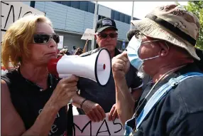  ?? (AP/Mike Stewart) ?? An anti-mask demonstrat­or (left) argues with a pro-mask demonstrat­or Thursday outside the Cobb County, Ga., School Board headquarte­rs in Marietta during a rally in support of masks in schools.