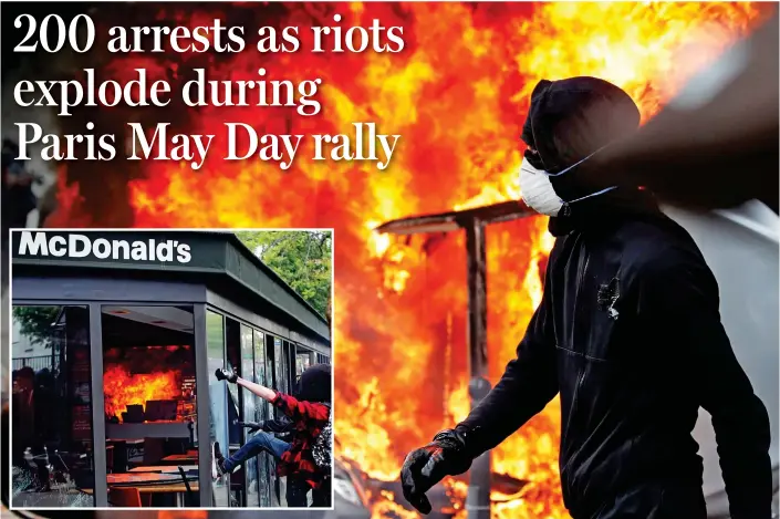  ?? ?? Fire and fury: A McDonald’s restaurant being vandalised and set alight by masked and hooded protesters during a violent May Day rally in Paris yesterday